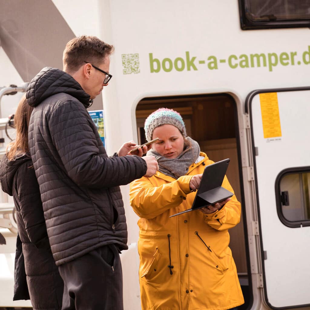 Zwei Personen im Gespräch vor einem Campervan eine Szene, die die Vorteile der Wohnmobil-Partnerschaft bei Book a Camper veranschaulicht.