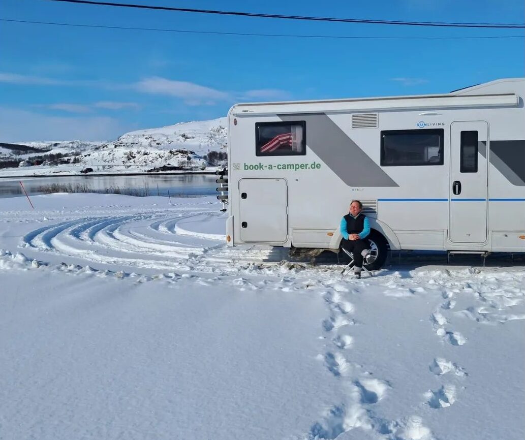 Campervan, geparkt in einer verschneiten Landschaft bei klarem Himmel, zur Veranschaulichung wichtiger Wetterüberleben-Tipps für Campervan-Reisende