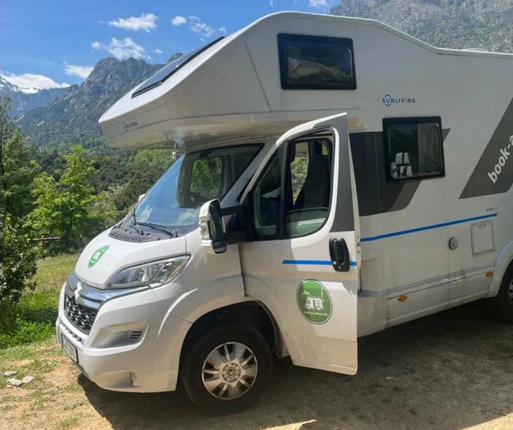 Wohnmobil kaufen: Wohnmobil mit Markise und offener Tür auf einem Campingplatz, bereit zur Besichtigung.