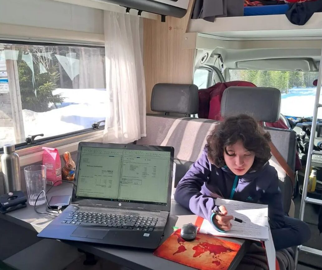 Woman working on laptop inside a campervan, showing how campervan internet helps travelers stay connected on the road.